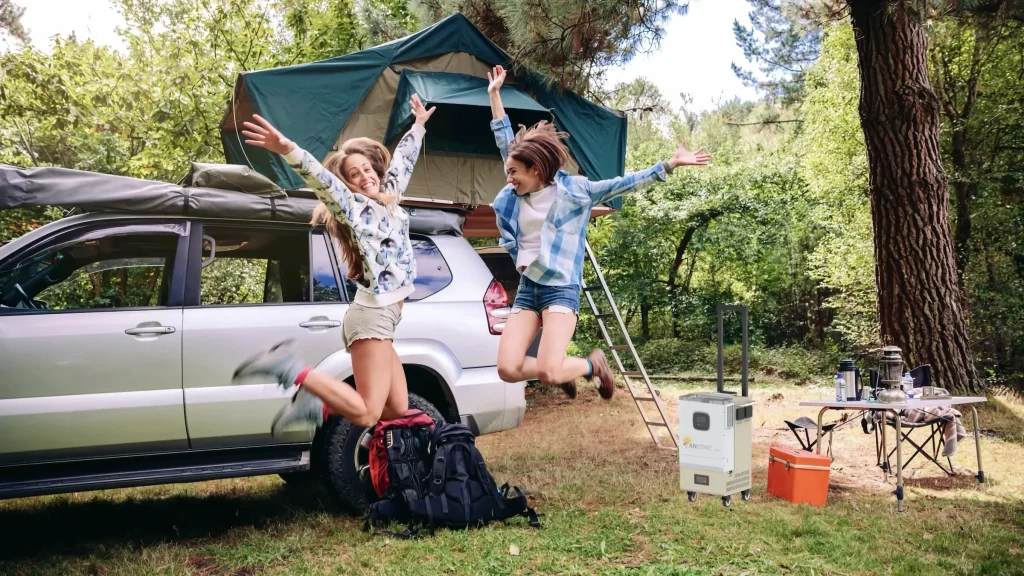 Two people jumping near campsite.
