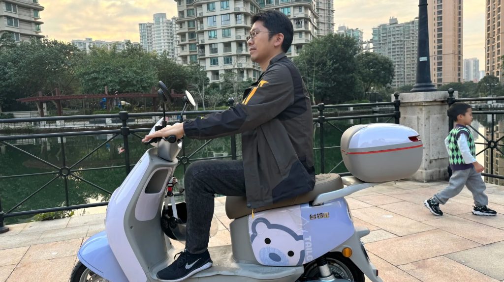 Person riding a scooter by water.