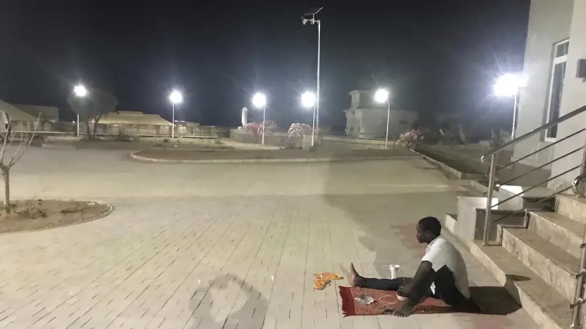 Man dining alone in illuminated courtyard.